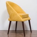 Mustard yellow velvet accent chair with curved back and wooden legs in a modern interior