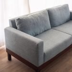 Modern Minimalist 2-Seater Sofa in light grey fabric with clean lines and tapered wooden legs in a stylish living room