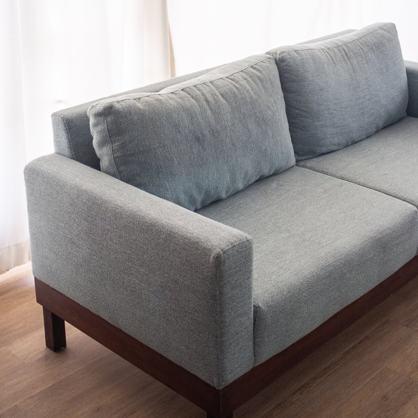 Modern Minimalist 2-Seater Sofa in light grey fabric with clean lines and tapered wooden legs in a stylish living room