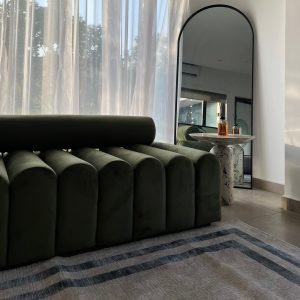 Caterpillar Bench with segmented curved design in natural wood and upholstered cushions placed in a modern entryway