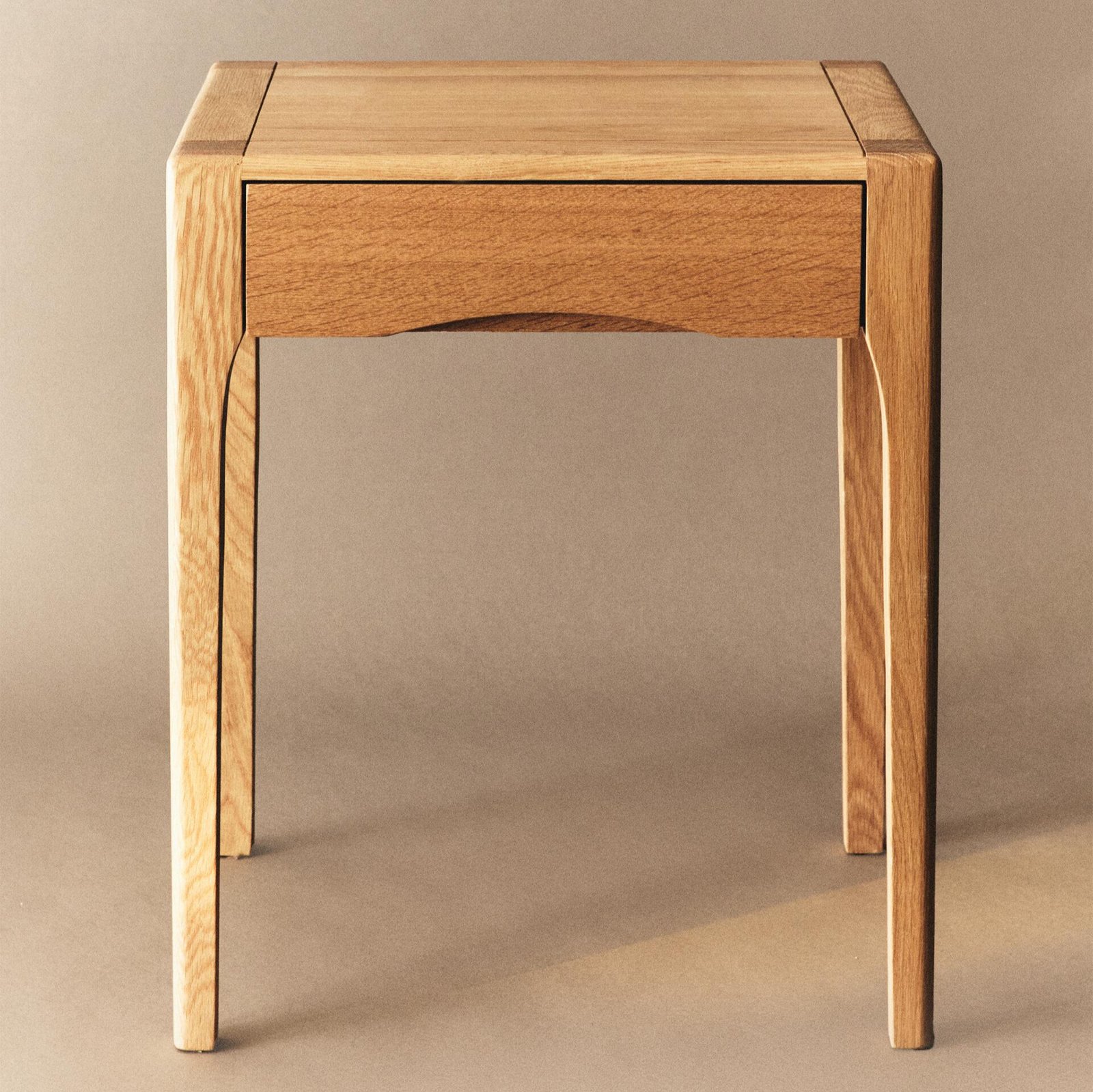 Modern nightstand with a drawer in walnut finish beside a cozy bed setup