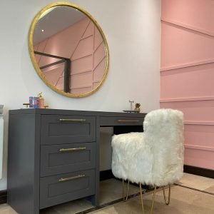 Elegant wooden dressing table with drawers, mirror, and upholstered stool in a cozy bedroom