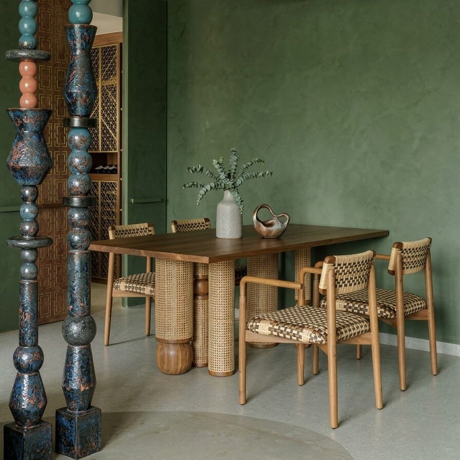 Luxury solid wood dining table with cane detailing and designer chairs in modern dining space