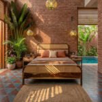A wooden bed with a cane headboard in a rustic bedroom with red brick walls, tropical plants, and a private pool view.