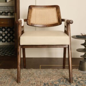Auro Cane Chair with walnut-tone wooden frame, natural woven cane backrest, rounded wooden armrests, and cream upholstered seat.